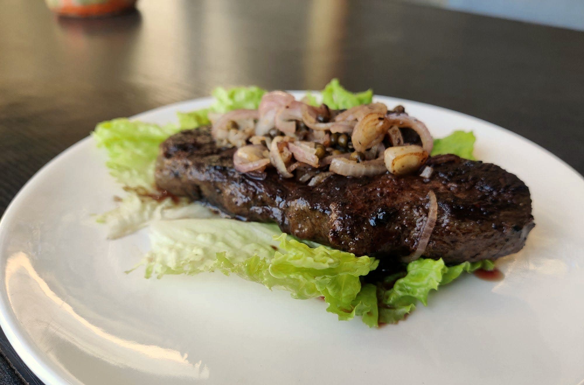 Pavé de bœuf grillé aux oignons sur lit de salade