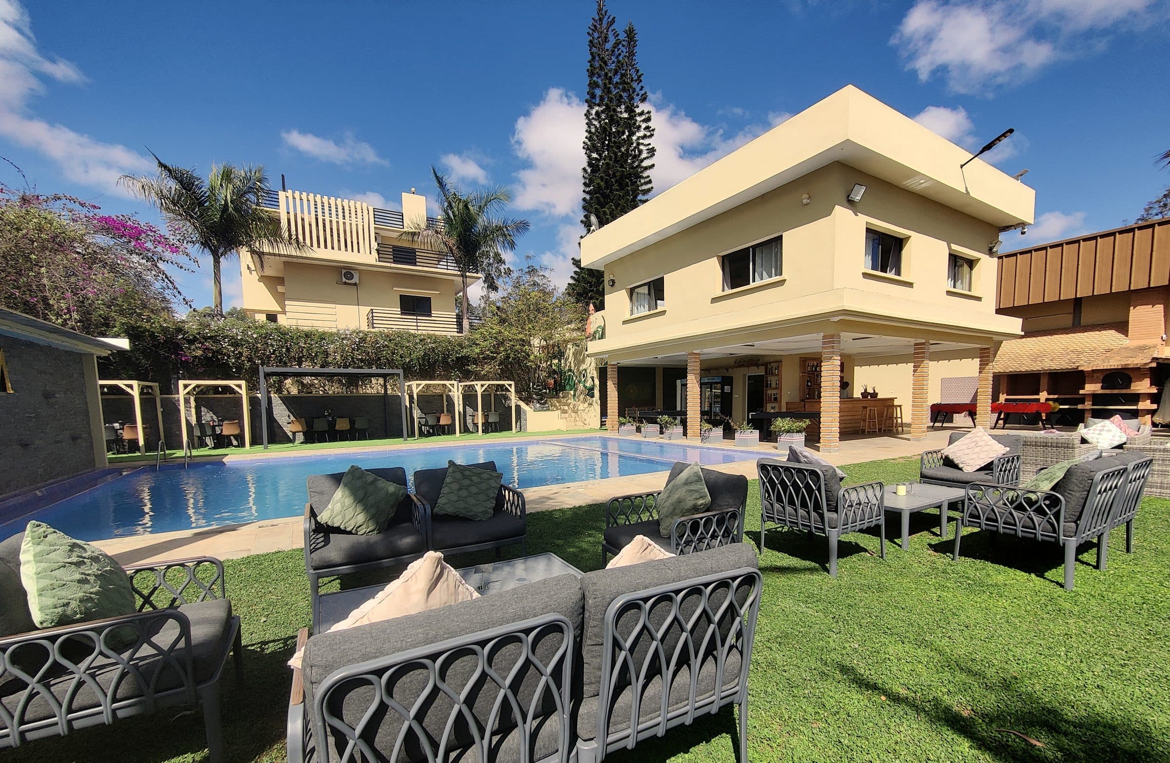 La villa du domaine, sa piscine et le salon de jardin sous les palmiers